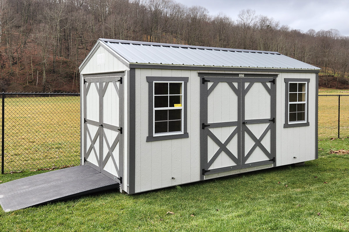 White and gray shed with X-pattern barn doors on grass