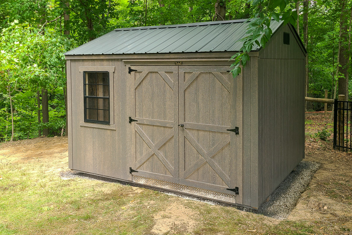 Storage shed with barn doors in a wooded backyard